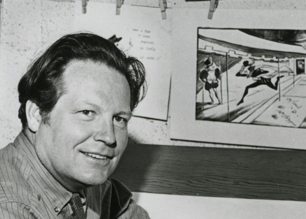 Photo of Don Freeman c. 1954 with  a drawing from Great Shakes in the background.