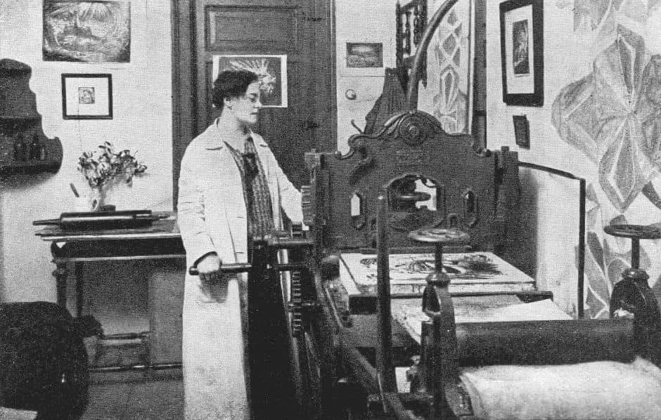 A 1923 photo of Helena Bochoráková-Dittrichová in a smock.
She is working at what appears to be a lithograph press.
Image credit: Wikipedia.